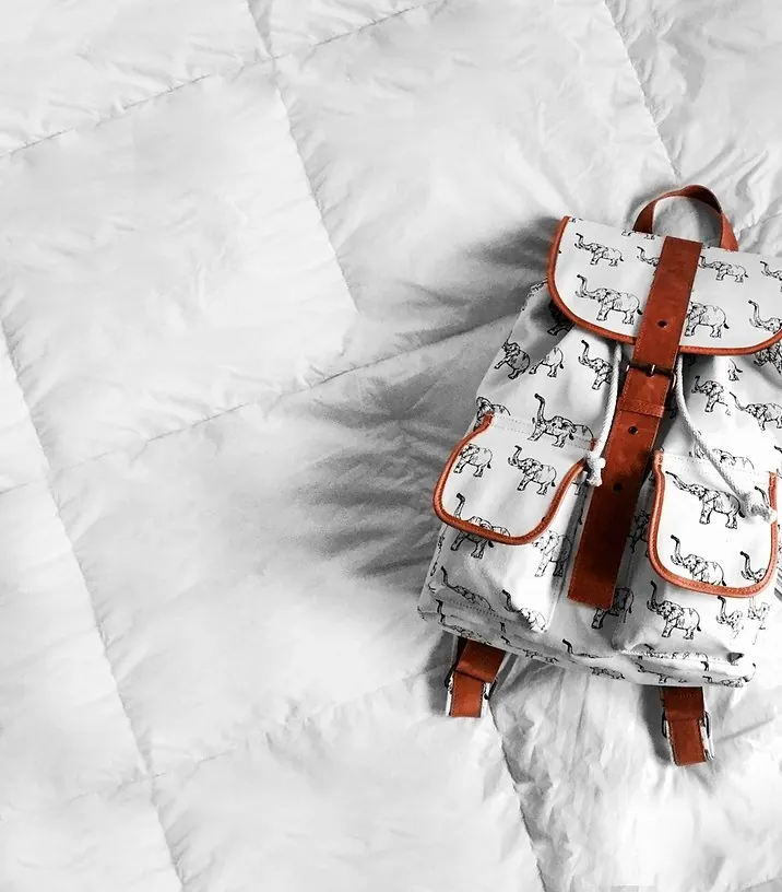Rucksack mit Vortaschen auf einer weißen Bettdecke