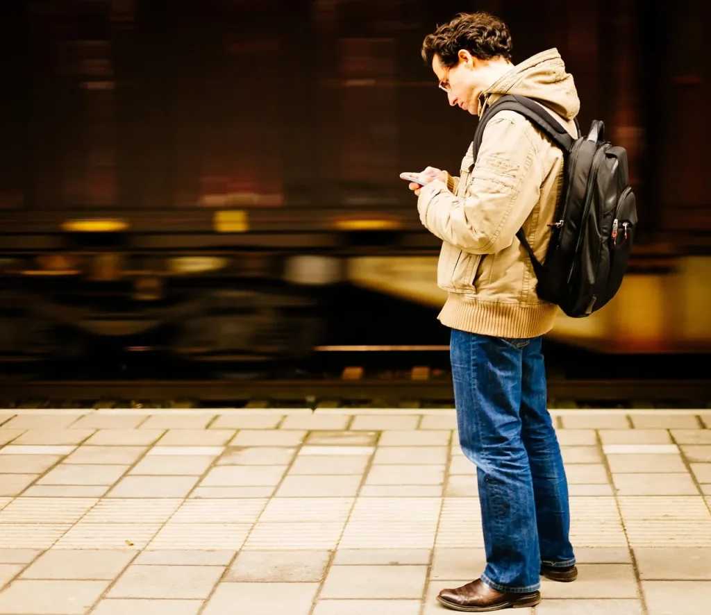 Mann mit Rucksack am Bahnsteig